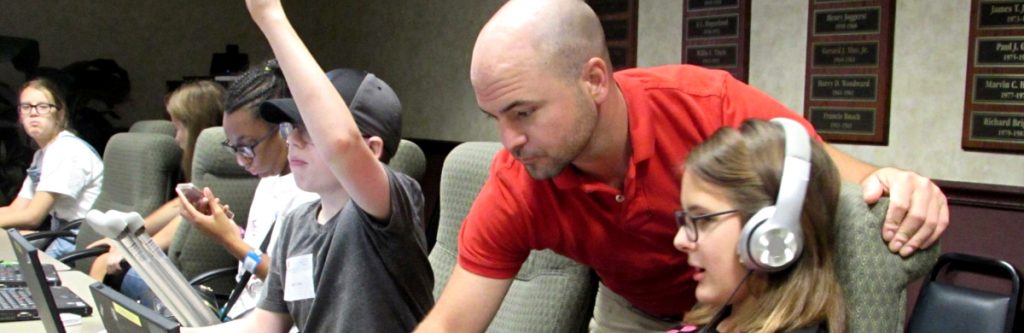 Volunteer man helping student on computer